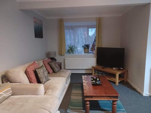 a living room with a couch and a tv at Fieldfare Green-Huku Kwetu Luton & Dunstable Spacious 4 Bedroom Detached House in Luton