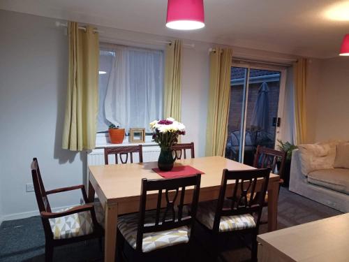 a dining room table with a vase of flowers on it at Fieldfare Green-Huku Kwetu Luton & Dunstable Spacious 4 Bedroom Detached House in Luton