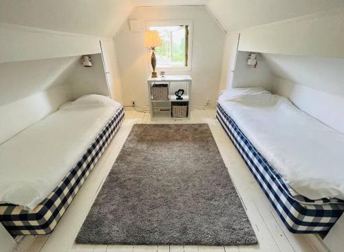 Duas camas individuais num quarto com um tapete em Fräsch villa med stor tomt & Hästens sängar em Mölnlycke