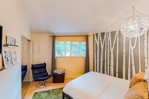 a bedroom with a bed and a chair and a chandelier at The Island Treehouse in Eastsound