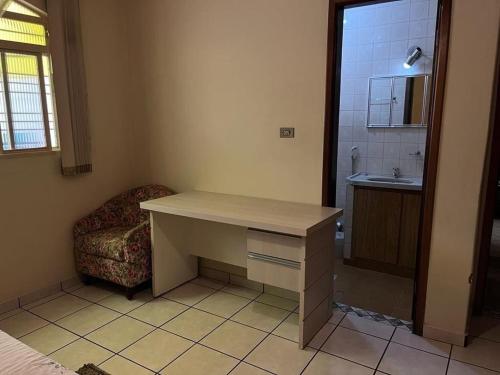 a room with a desk and a chair and a sink at Pousada Lopes na Fama in Goiânia