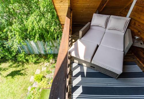 an outdoor bed with white cushions on a porch at Mannana házikó in Szokolya