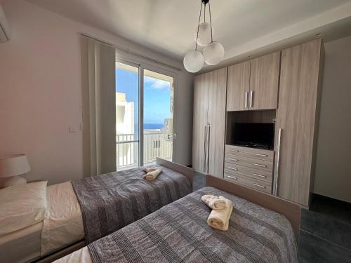 um quarto de hotel com duas camas e uma grande janela em Del Mar Apartment! em Żebbuġ