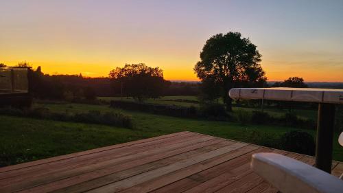 une terrasse en bois avec un coucher de soleil en arrière-plan dans l'établissement Studio L'audrerie., à Saint-Pardoux-Corbier