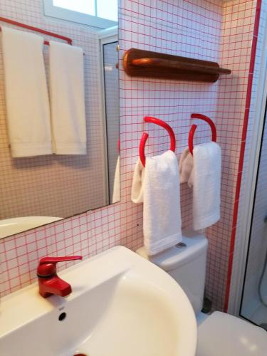 a bathroom with a sink and a toilet with towels at Varandas Miramar in Angra do Heroísmo