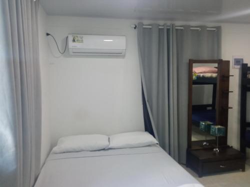 małą sypialnię z łóżkiem i lustrem w obiekcie Posada Valerie w mieście Providencia