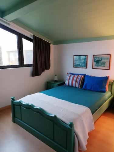 a bedroom with a green bed in a room with windows at Varandas Miramar in Angra do Heroísmo