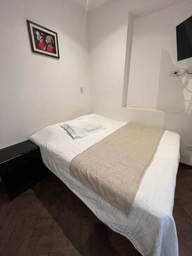 a small white bedroom with a bed and a picture on the wall at Departamento Centro Jujuy 2 in San Salvador de Jujuy