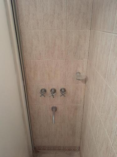 een douche met twee knoppen in een douche bij Apart Begonia, 1 dor con patio de luz in Río Cuarto