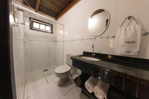 y baño con aseo, lavabo y espejo. en Residencial Caminho das Ondas, en Bombinhas