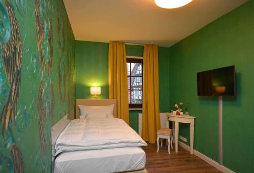 ザクセンハイムにあるHotel am Kirchplatzの緑の壁、ベッド付きのベッドルーム1室