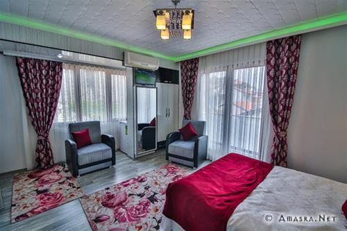 a bedroom with a bed and two chairs and a television at Kural Butik Pansiyon in Amasra