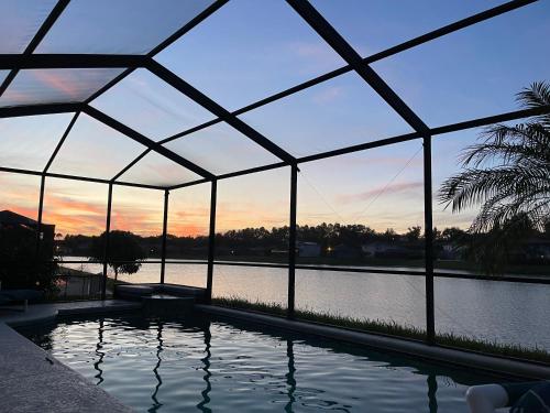 a swimming pool in a glass house with a view of the water at Its A Dream Family Vacation Rental - Minutes from Disney in Kissimmee