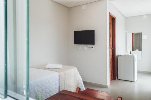 um quarto branco com uma cama e uma televisão na parede em Pousada Estrela do Mar em Barra Grande
