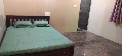 a bed with green sheets and pillows in a room at S B h in Gokarn