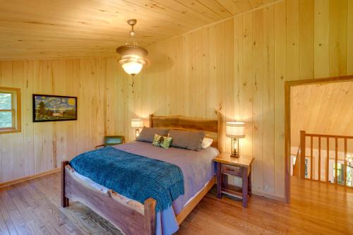 1 dormitorio con 1 cama en una habitación con paredes de madera en Riverfront West Virginia Cabin with Screened-In Deck, en Marlinton
