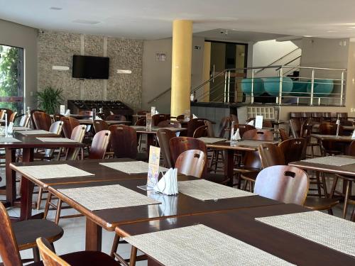 a dining room with tables and chairs and a television at Atrium Confort Hotels in Parauapebas