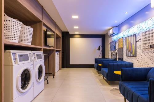 a laundry room with a washing machine and blue chairs at Helbor Stay Batel in Curitiba