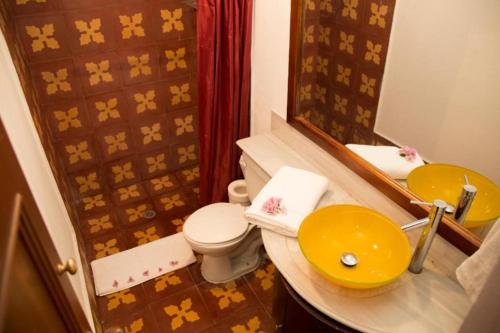 uma casa de banho com um lavatório amarelo e um WC. em Casa Carmelita Hotel Boutique Pitalito em Pitalito