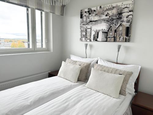 um quarto com uma cama com lençóis brancos e uma janela em Aurora Penthouse em Rovaniemi