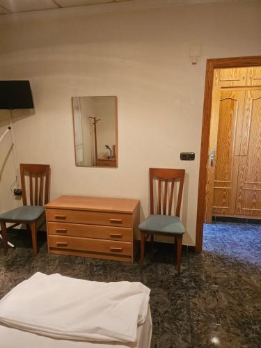 um quarto com 2 cadeiras, uma cómoda e um espelho em Hotel restaurante Palacio Fes em Múrcia