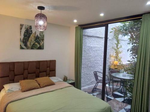 Schlafzimmer mit einem Bett, einem Tisch und einem Fenster in der Unterkunft Jardines Ambato in Ambato