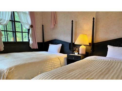 a bedroom with two beds and a lamp and a window at Restaurant & Hotel Traumerei - Vacation STAY 47760v in Hakuba