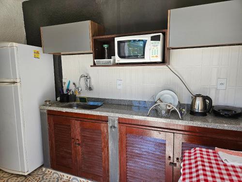 a small kitchen with a sink and a microwave at Suite Dupla em Búzios in Búzios