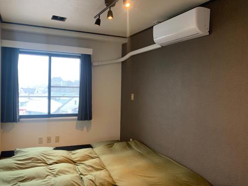 een slaapkamer met een bed, een raam en airconditioning bij Kawamura Building 3F - Vacation STAY 47042v in Kusatsu