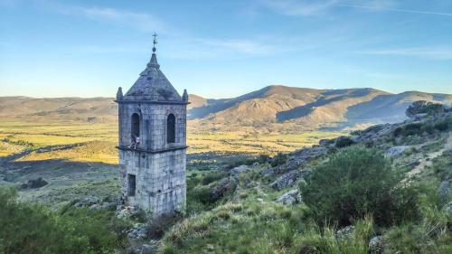 uma velha torre de pedra numa colina com montanhas ao fundo em Casa La Charca 