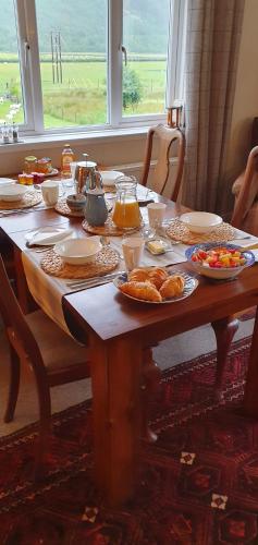ein Holztisch mit Tellern voller Essen darauf in der Unterkunft Clachan Farmhouse B & B in Ullapool