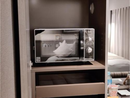 un forno a microonde seduto sopra uno scaffale di Hotel Grand View Takasaki - Vacation STAY 55422v a Takasaki