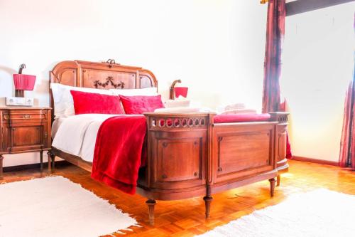 um quarto com uma cama de madeira e almofadas vermelhas em Fonte da Rosa Guest House em Belmonte