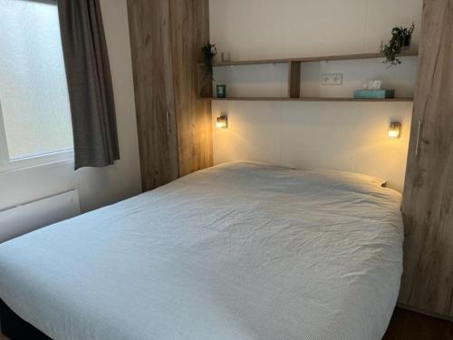 een slaapkamer met een groot wit bed en een raam bij Moderne chalet met airco in Blankenberge in Blankenberge