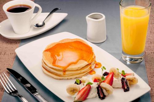 a plate of pancakes and fruit and a glass of orange juice at Camino Real Antigua in Antigua Guatemala