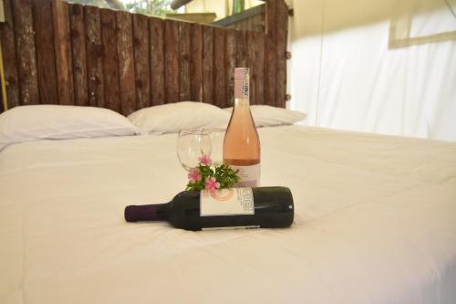 - Botella de vino y copa en la cama en Eco-Glamping Panorama, en Monterrey