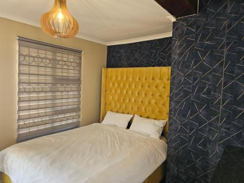 a bedroom with a bed with a yellow headboard at YELLO GUEST HOUSE CE2 in Vanderbijlpark