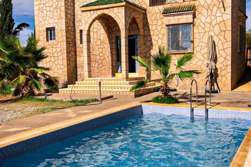 a house with a swimming pool in front of a house at احجز الآن وعش تجربة إقامة لا تُنسى في مدينة الصويرة الساحرة. in El Khemis des Meskala