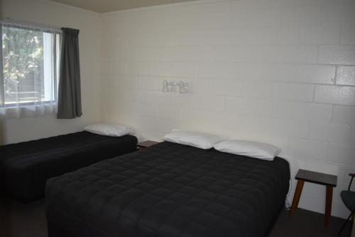 a hotel room with two beds and a window at Pukenui Lodge Motel in Pukenui
