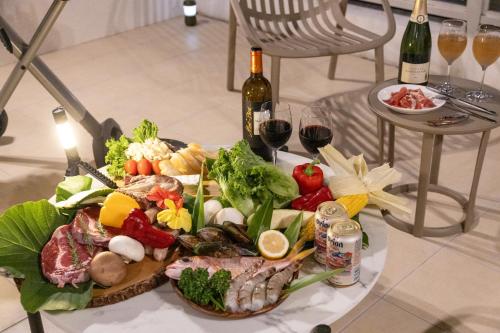 a plate of food on a table with bottles of wine at Alpha Terrace Onna Hills in Onna
