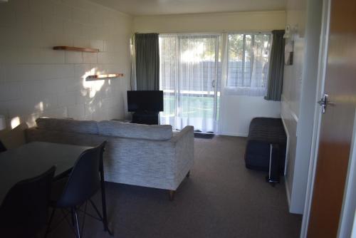a living room with a couch and a television at Pukenui Lodge Motel in Pukenui