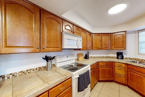 a kitchen with wooden cabinets and a white stove top oven at Tierra Catalina #91 in Tucson