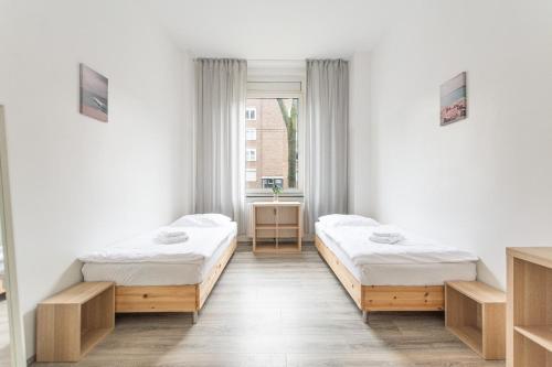 two beds in a room with a window at T&K Apartments - 2 Room Apartment - Ground Floor in Düsseldorf