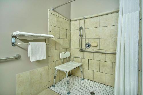ein Bad mit einer Dusche mit einem Hocker in der Unterkunft Studio 6-Bakersfield, CA in Bakersfield