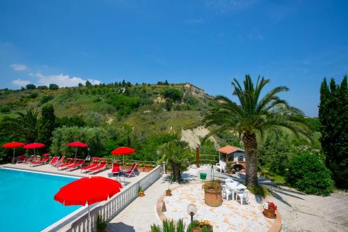 a resort with a pool with red umbrellas and a mountain at La Panoramica Country House in San Benedetto del Tronto