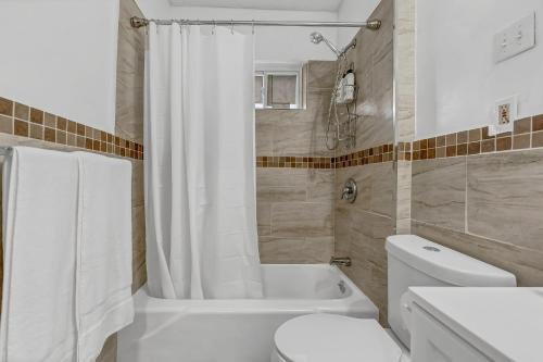 a bathroom with a toilet and a tub and a sink at Renovated Main Floor Large 3 Bed House in Buffalo