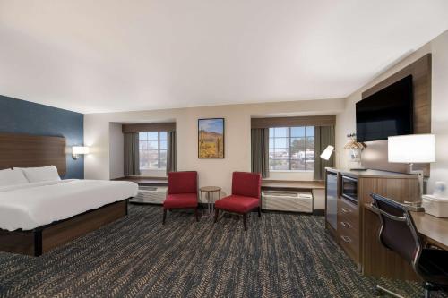 Habitación de hotel con 1 cama y 2 sillas rojas en Best Western Bellemont Shadow Mountain Inn en Flagstaff