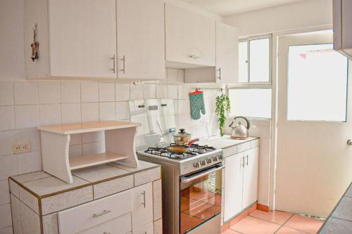 La cuisine est équipée de placards blancs et d'un four avec plaques de cuisson. dans l'établissement Mountain Home, à Huaraz