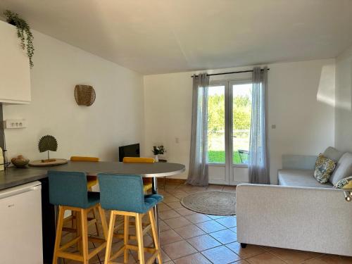 uma cozinha e sala de estar com mesa e cadeiras em Le cosy cottage d'Alex em Ardon