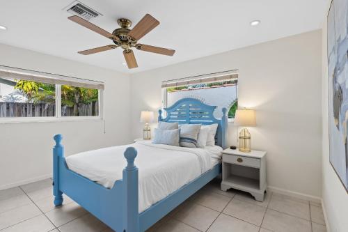 a blue bed in a white bedroom with a ceiling fan at Solar Heated Pool Spa Tiki Hut Huge Backyard Hammock Retro Bikes in Pompano Beach